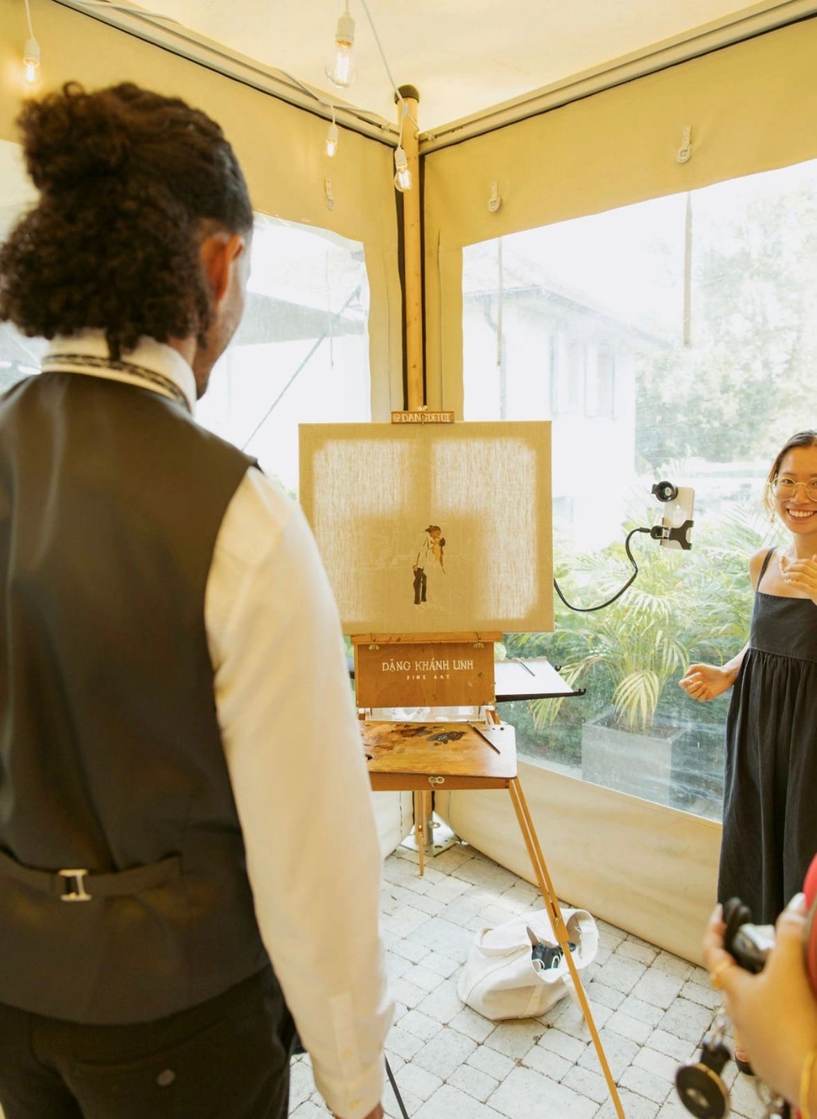 Hochzeitsgäste schauen zu, wie die Live-Hochzeitsmalerei auf der Staffelei im Petit Manoir in Morges Gestalt annimmt. Fotografie: Green Moon Photography.