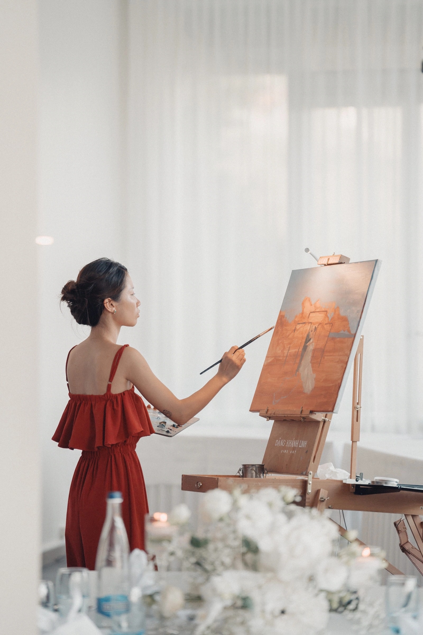 Khanh Linh Dang dipinge al cavalletto in abito rosso a un matrimonio all’Hôtel Préalpina, Chexbres.