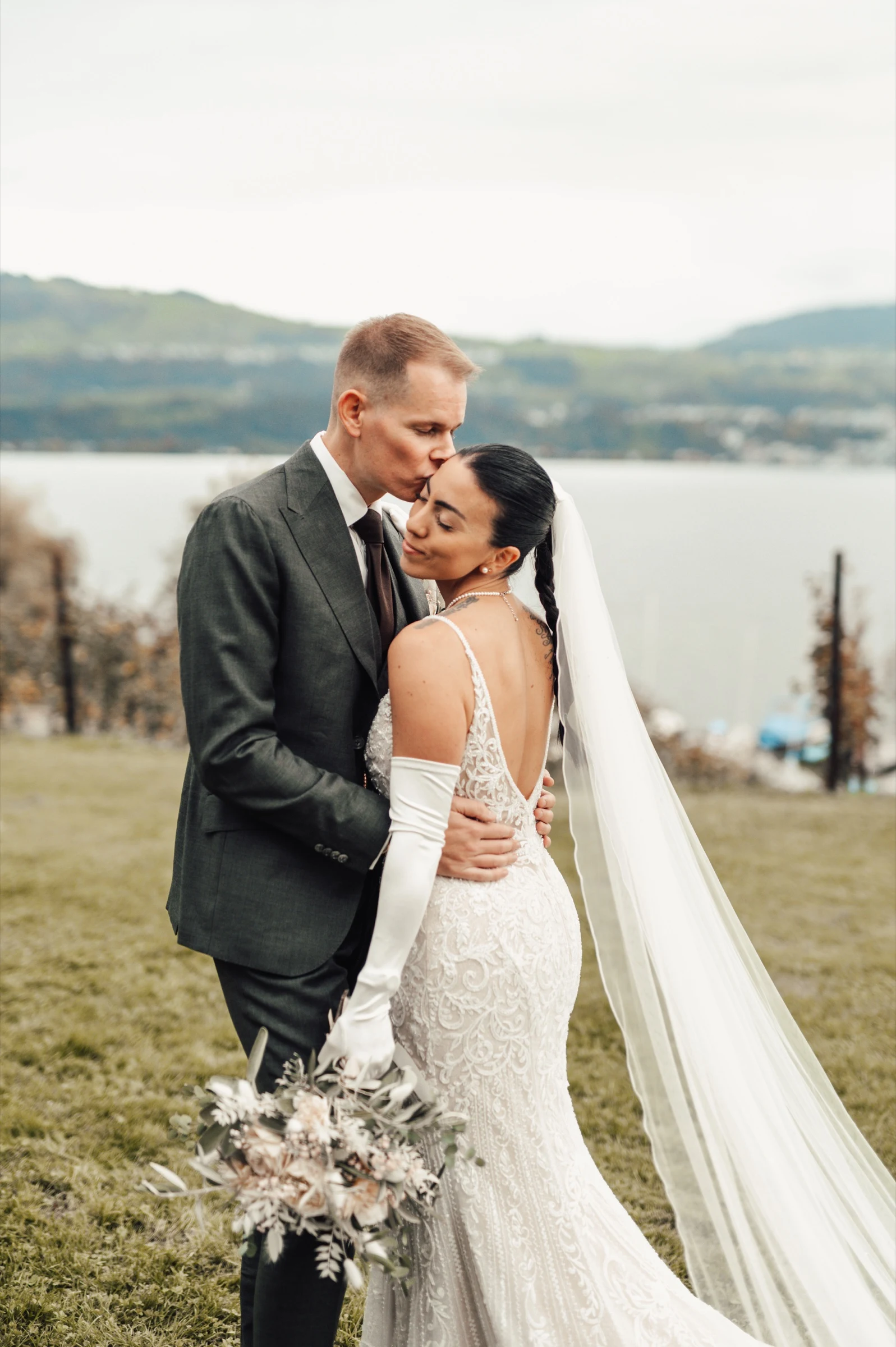Bride and groom embracing in front of Lake Zurich at Moschti Stäfa. Photography by Geraldine Rhyner Fotografie.