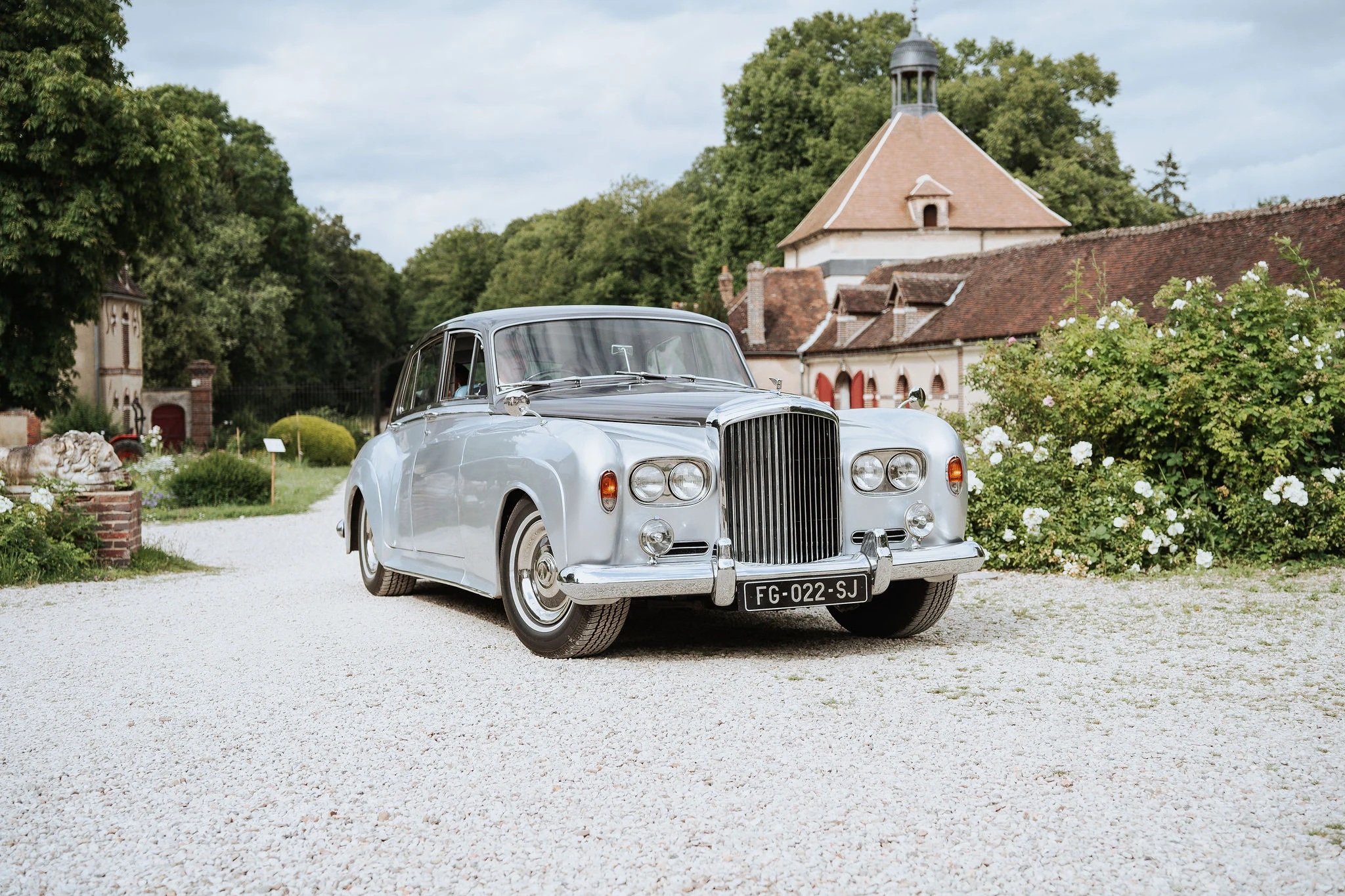 Vintage wedding car arriving at the entrance of the historic Chateau du Fey in Burgundy.
