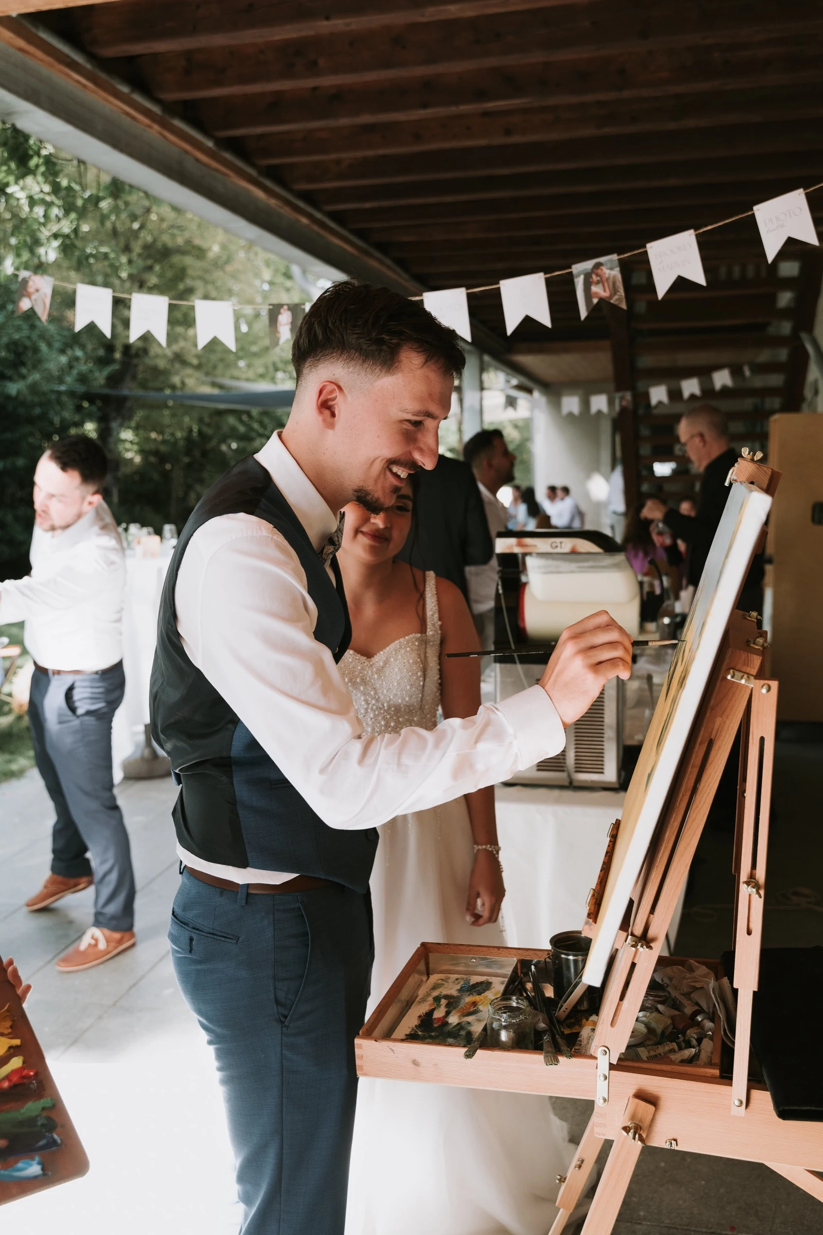 The groom smiling as he paints a few strokes on the canvas