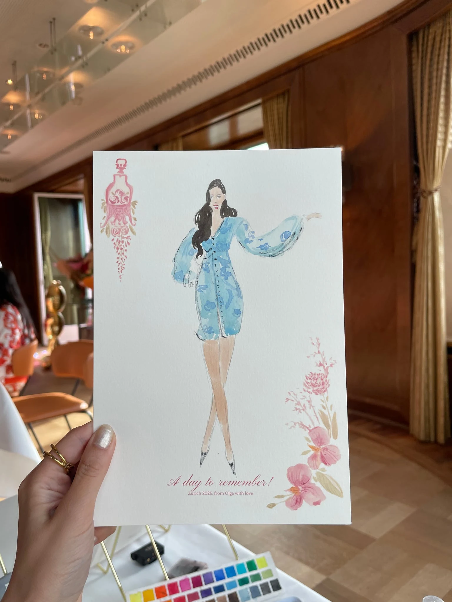 Live watercolor illustration of a guest in a blue mini dress with puff sleeves at a birthday party at AMERON Zürich Bellerive au Lac.