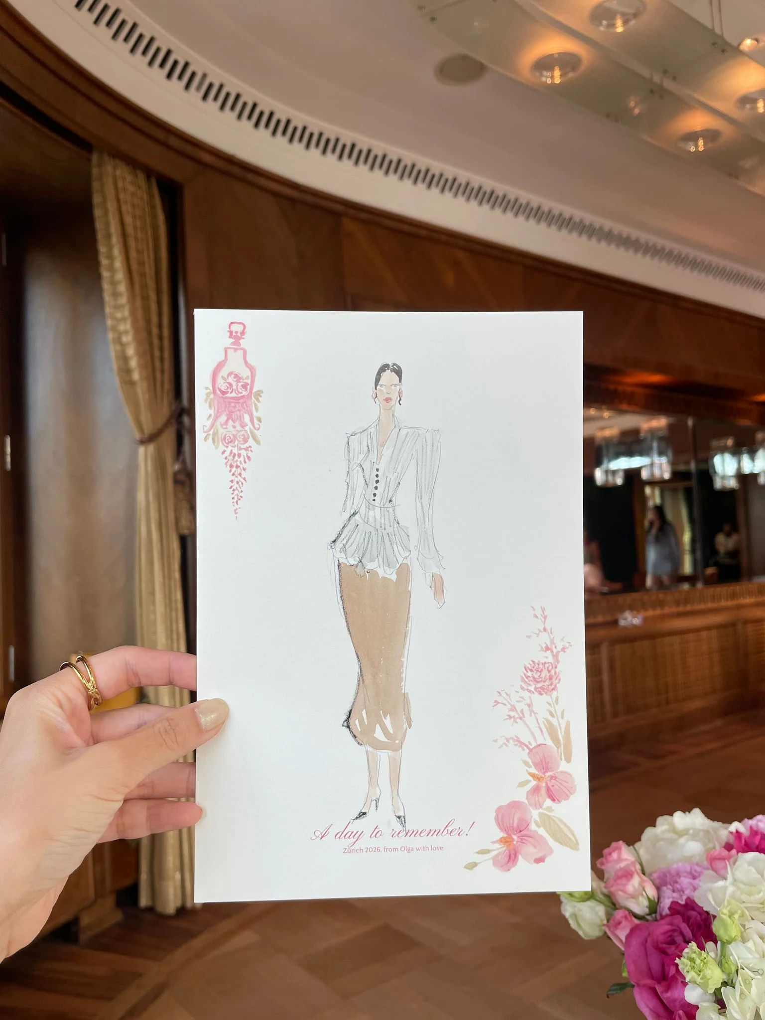 Live watercolor illustration of a guest in a white blouse and beige trousers at a birthday party at AMERON Zürich Bellerive au Lac.