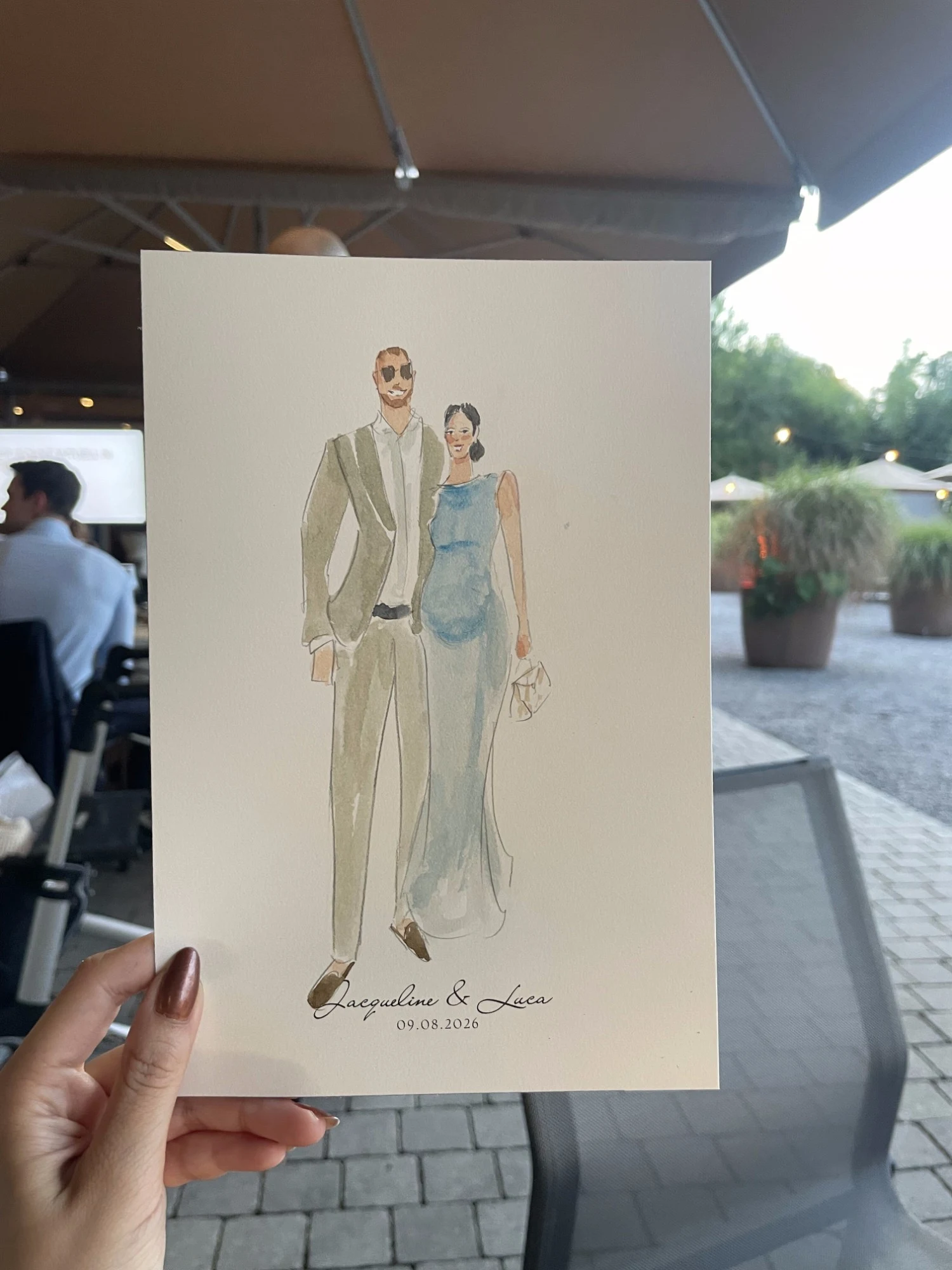Live watercolor portrait of a guest couple: a man in sunglasses and a beige suit, a woman in a blue dress.