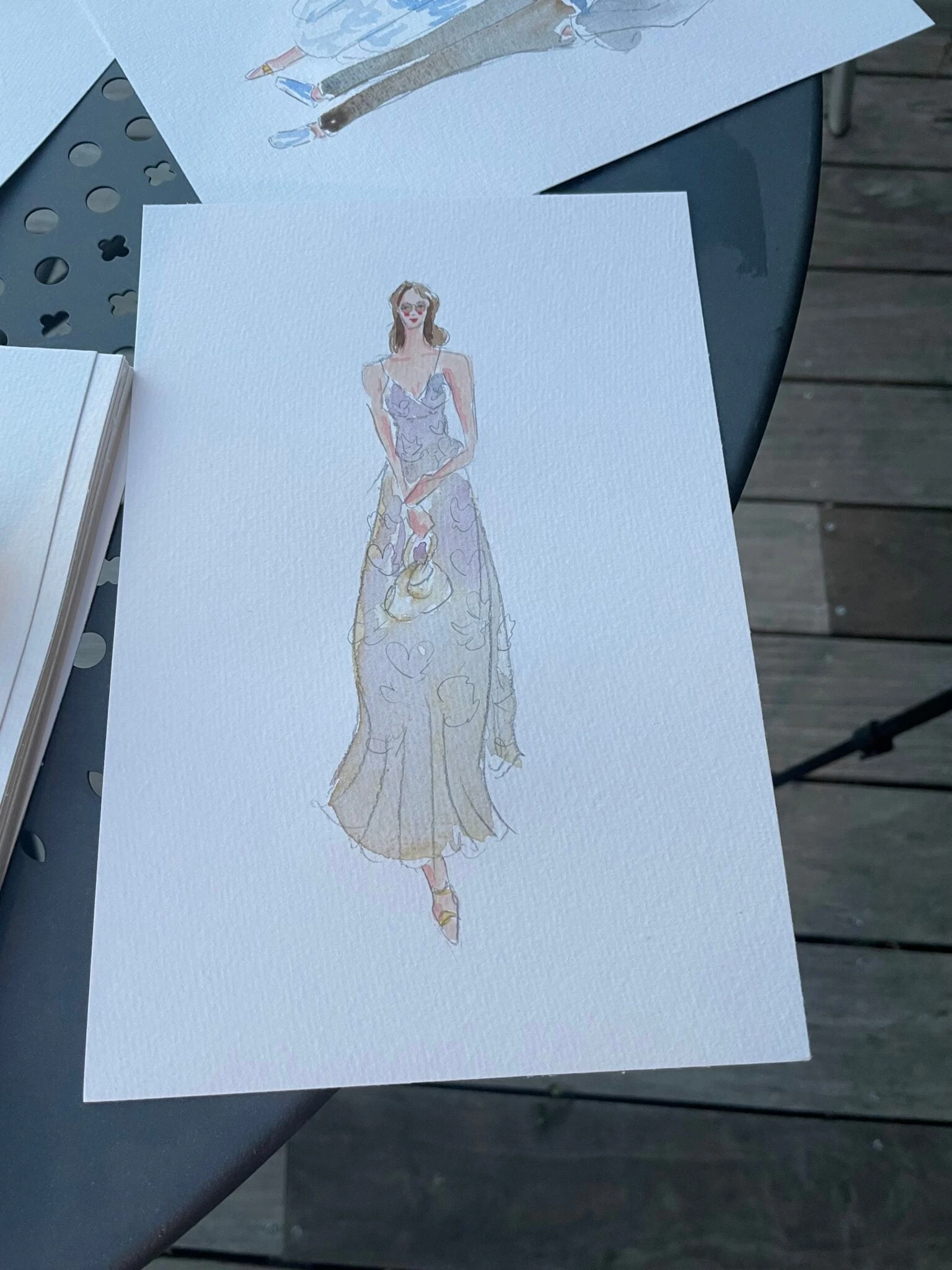 Live watercolor portrait of a wedding guest in a violet floral dress with a handbag.