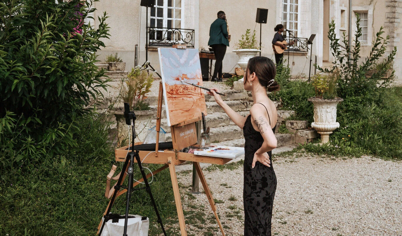 Linh Dang painting a canvas with the singer and saxophonist performing in the background at Château du Feÿ. Photography by Kimmak Design.