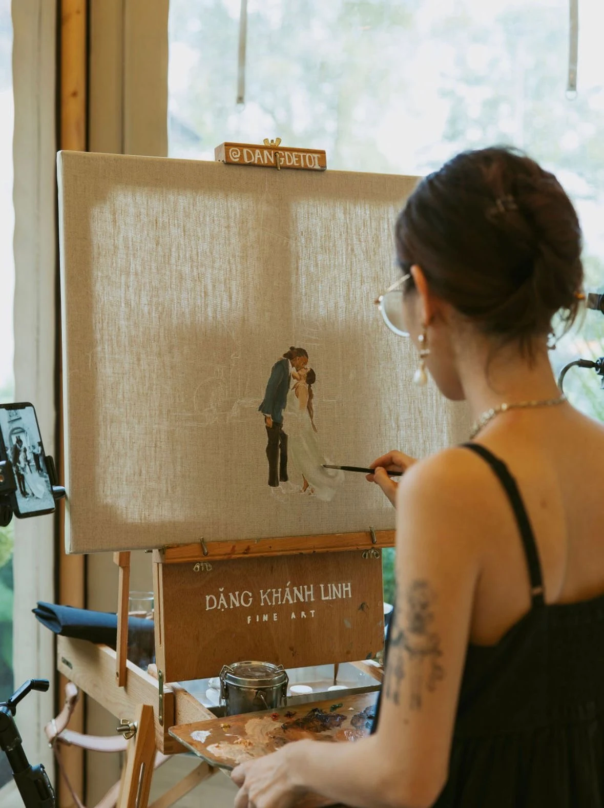 Live wedding painter adding the final details to the bride and groom’s kiss on a canvas. Photography by Green Moon Photography.