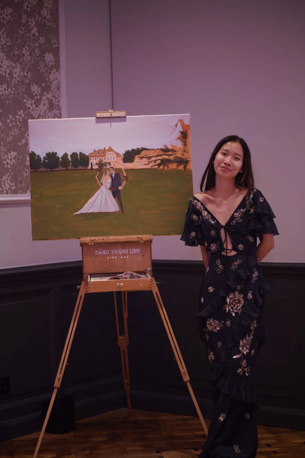Live wedding painter posing beside her live wedding painting of Château de la Tour at the end of the wedding. Photography by @pichou_.