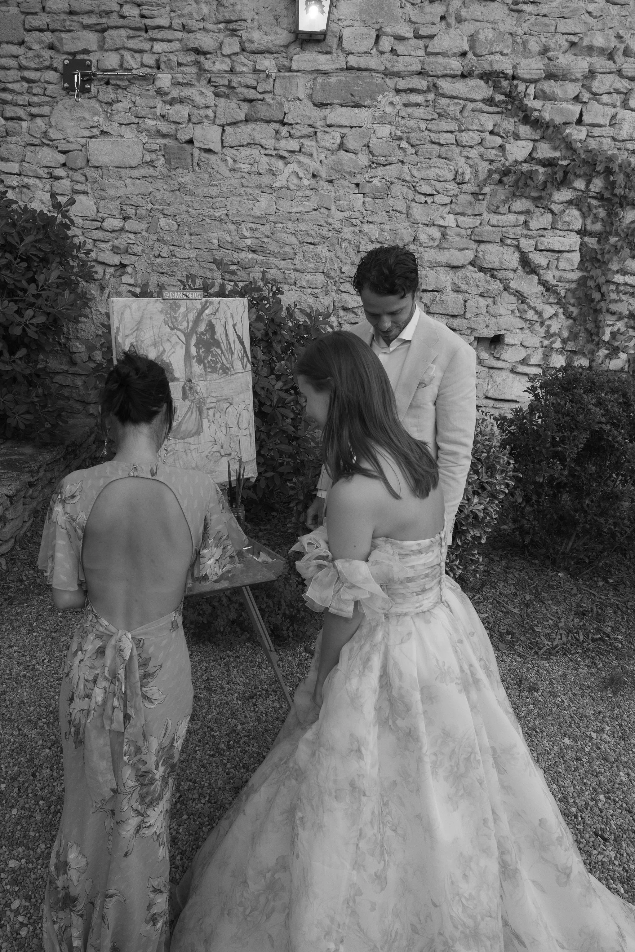 The bride and groom watching Linh paint their wedding at the easel, La Bastide de Laurence, Provence. © Danielle Villarreal