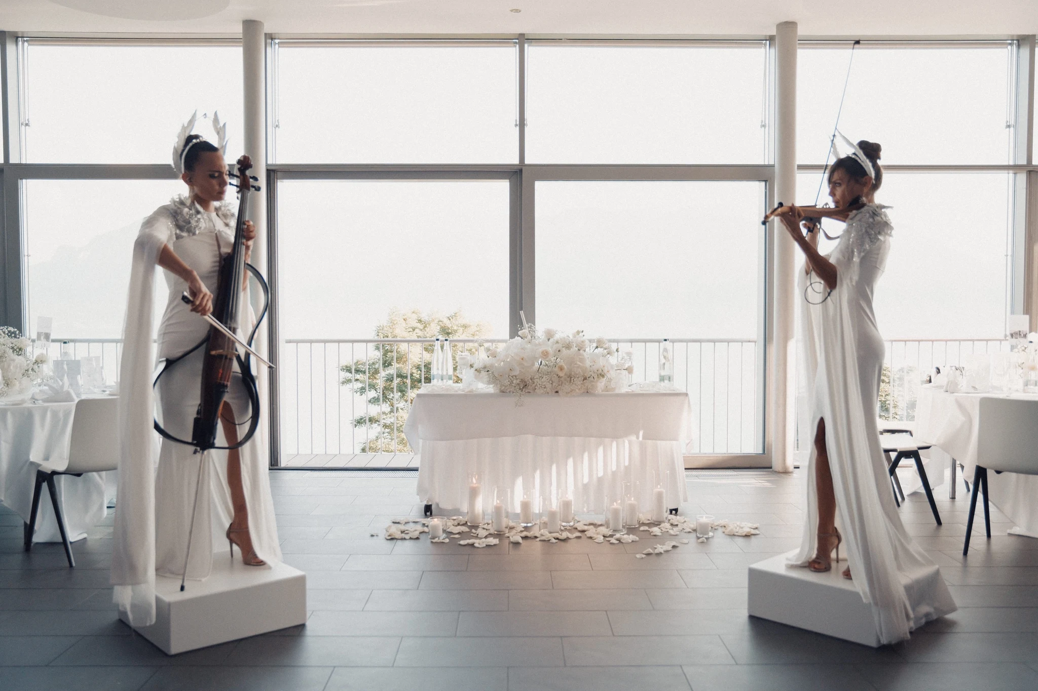 Cellist and violinist in white gowns performing in front of Lake Geneva at Hôtel Préalpina.
