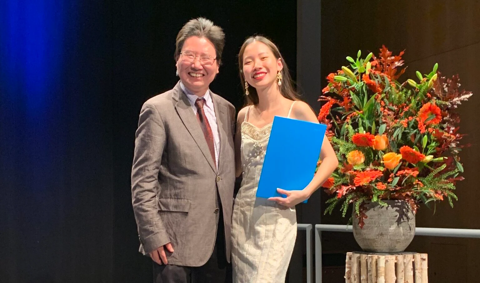 Khanh Linh Dang holding her Political Science diploma with her father during graduation ceremony