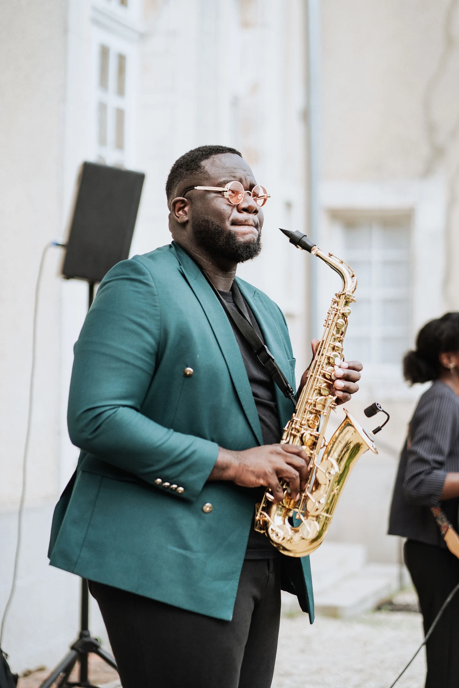 A saxophonist performing live during the outdoor wedding cocktail at Château du Feÿ. Photography by Kimmak Design.