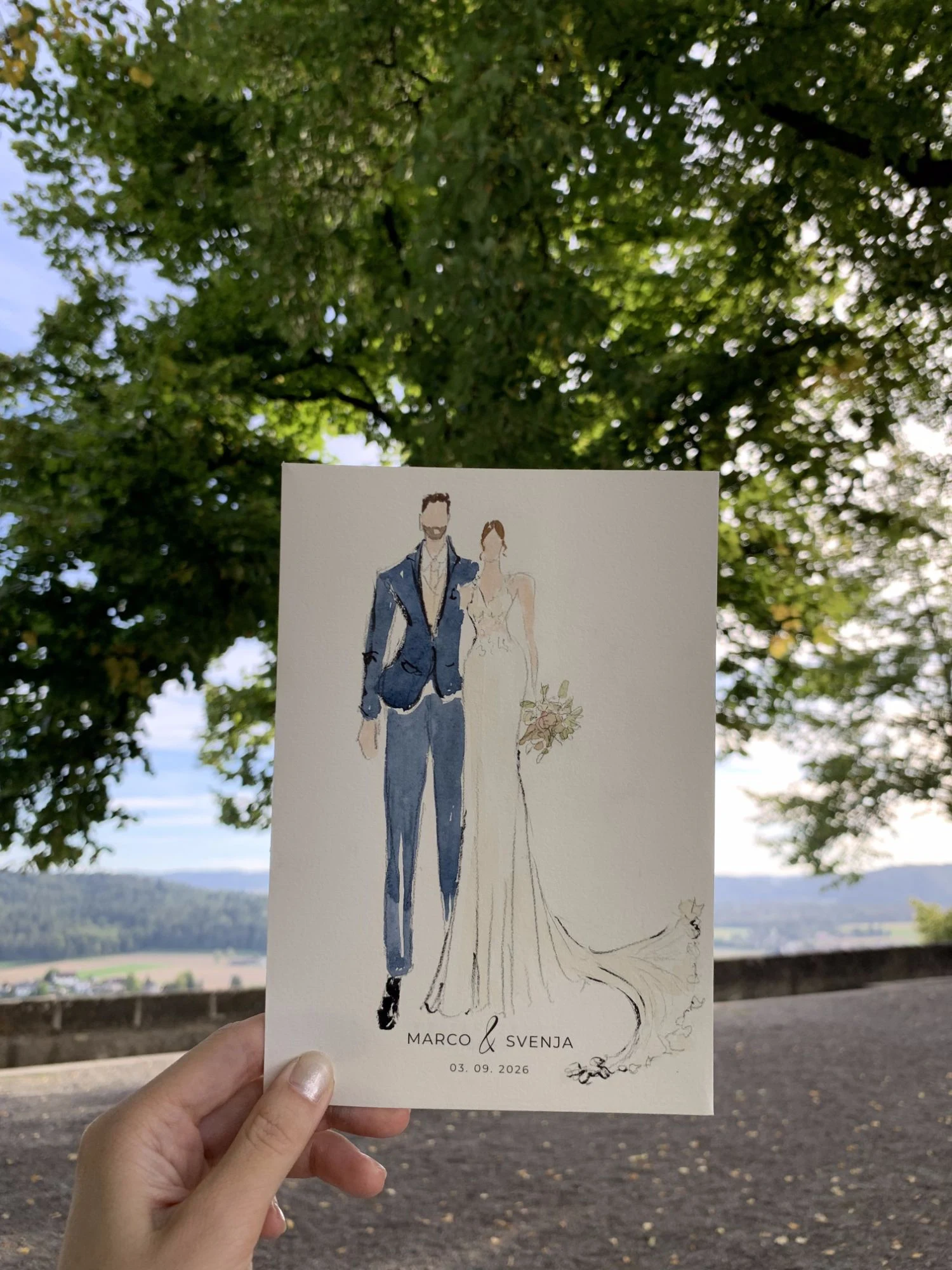 Live watercolor fashion sketch of the bride and groom at Schloss Lenzburg: a navy suit and a lace gown with a long train.