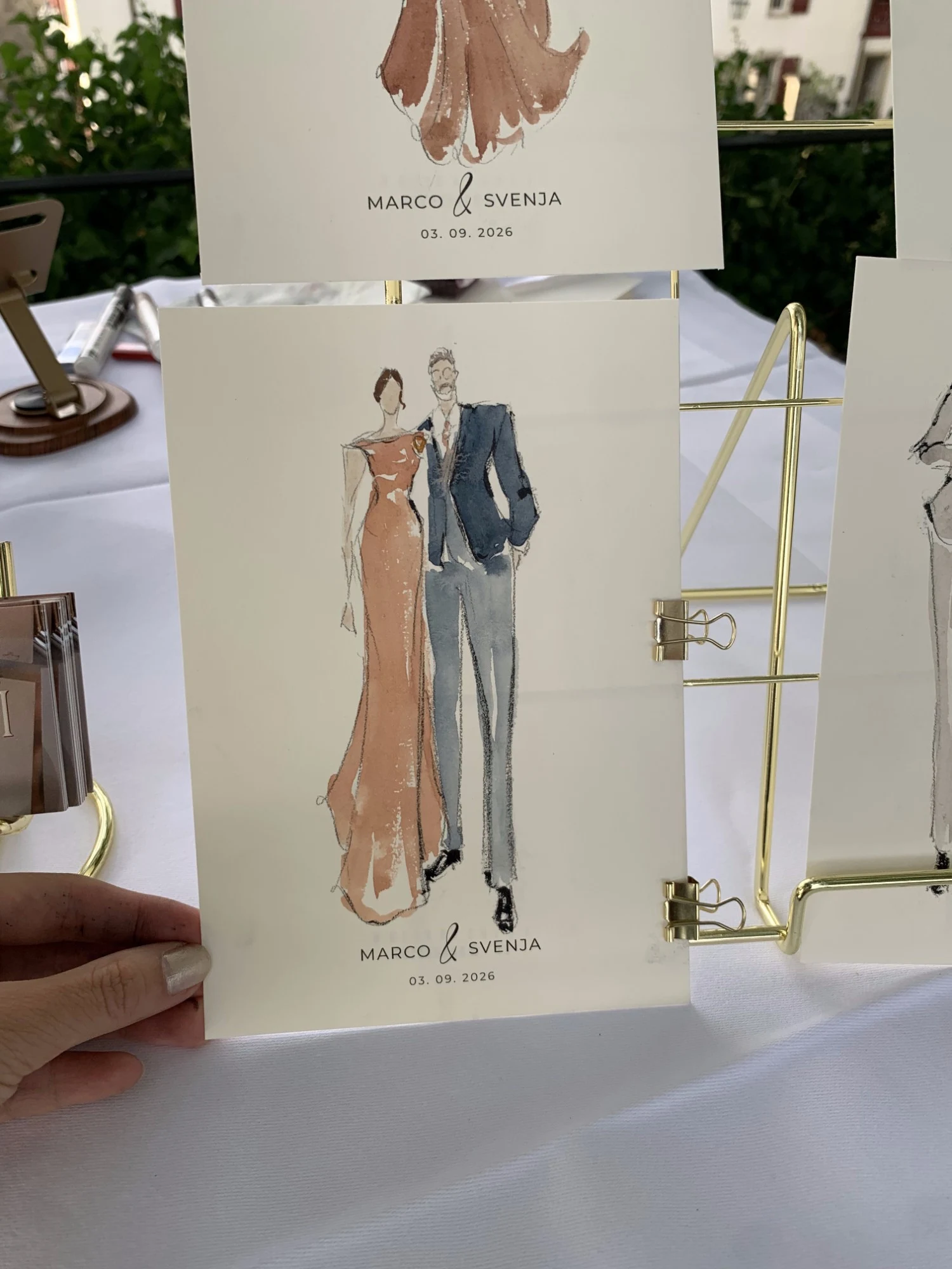 Live watercolor fashion sketch of a guest couple at Schloss Lenzburg: a coral gown and a navy blazer.