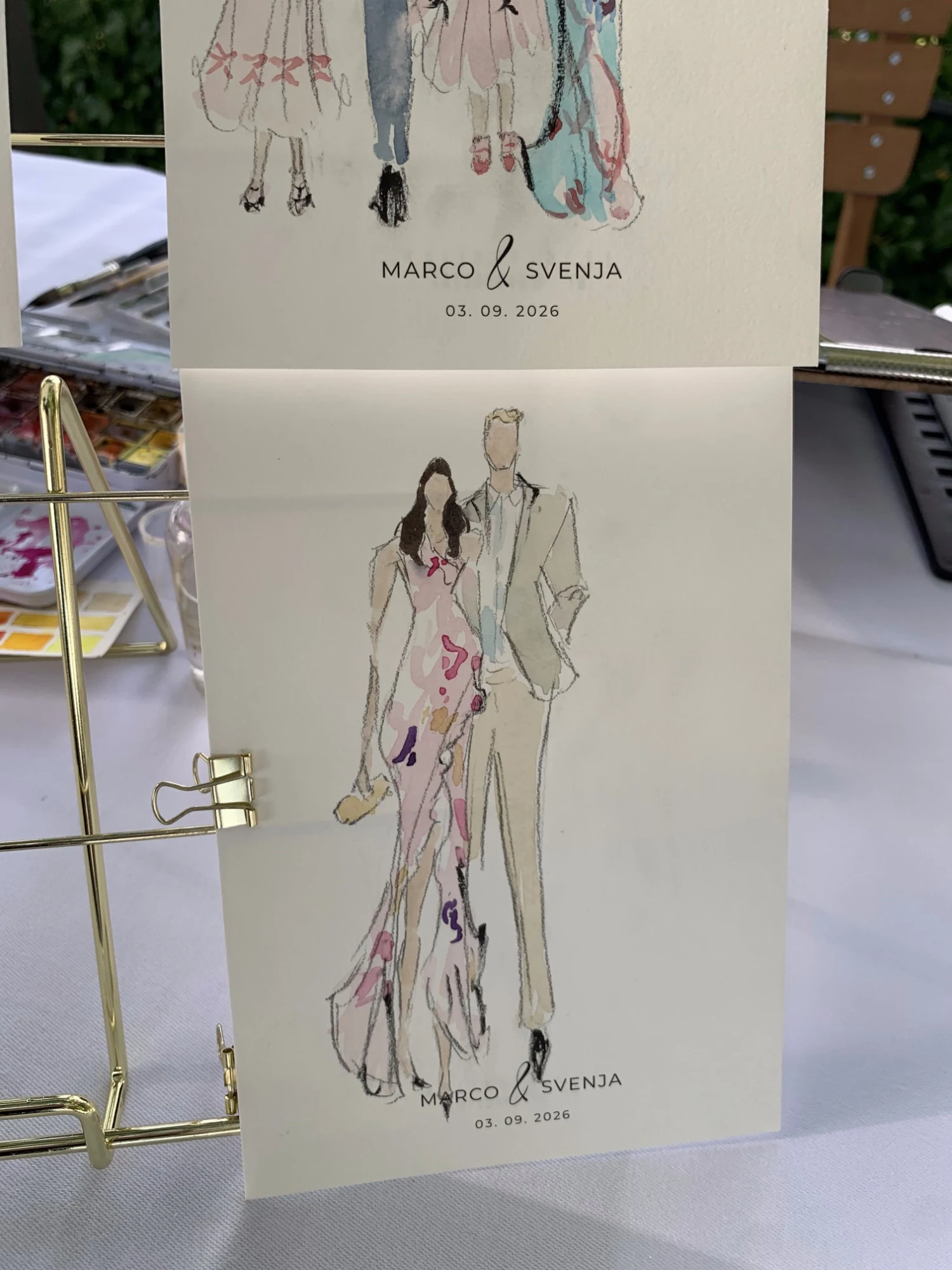 Live watercolor fashion sketch of a guest couple at Schloss Lenzburg: a pink floral gown and a beige suit.