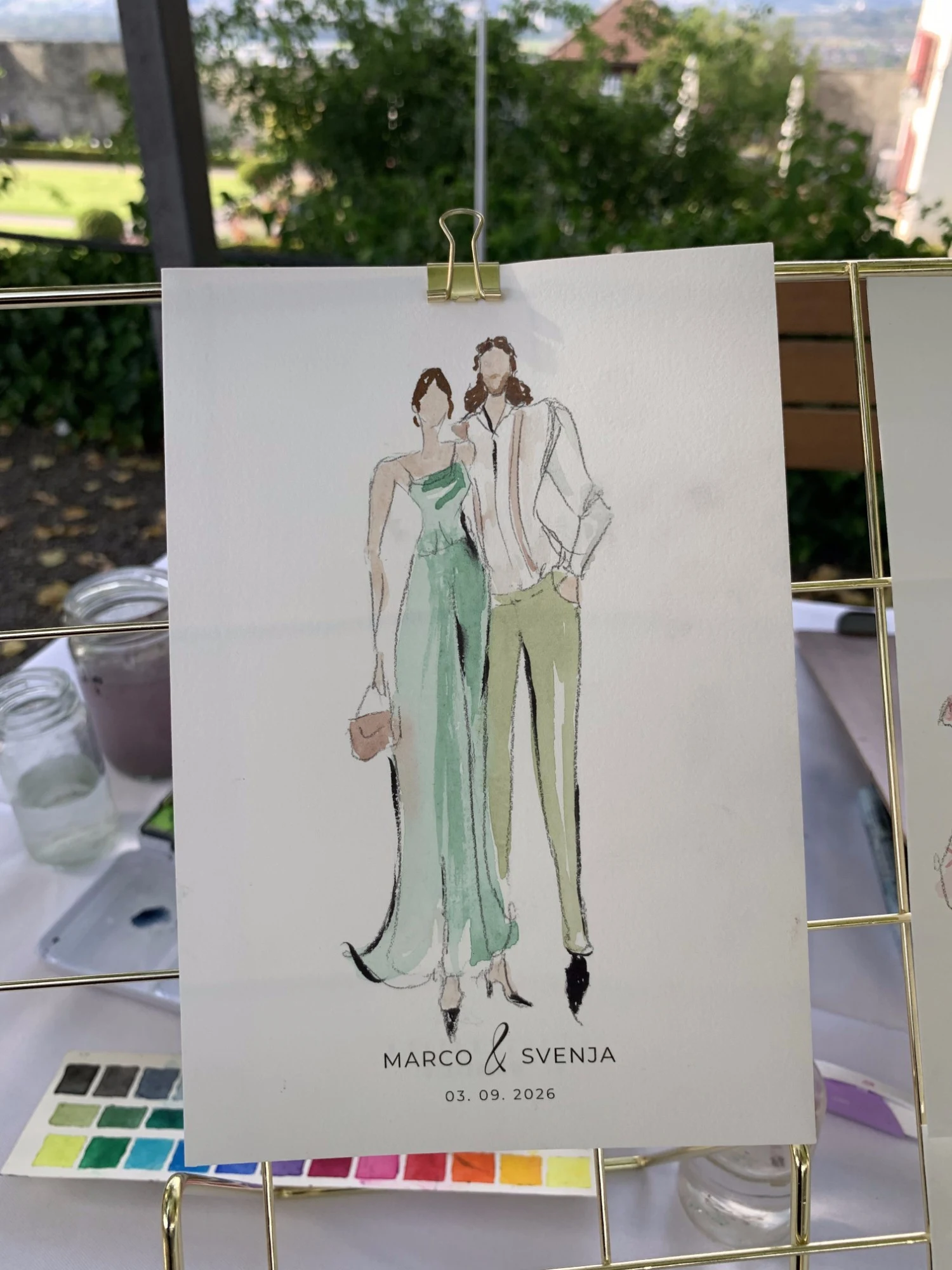 Live watercolor fashion sketch of a guest couple at Schloss Lenzburg: a green satin gown and a white shirt with olive trousers.