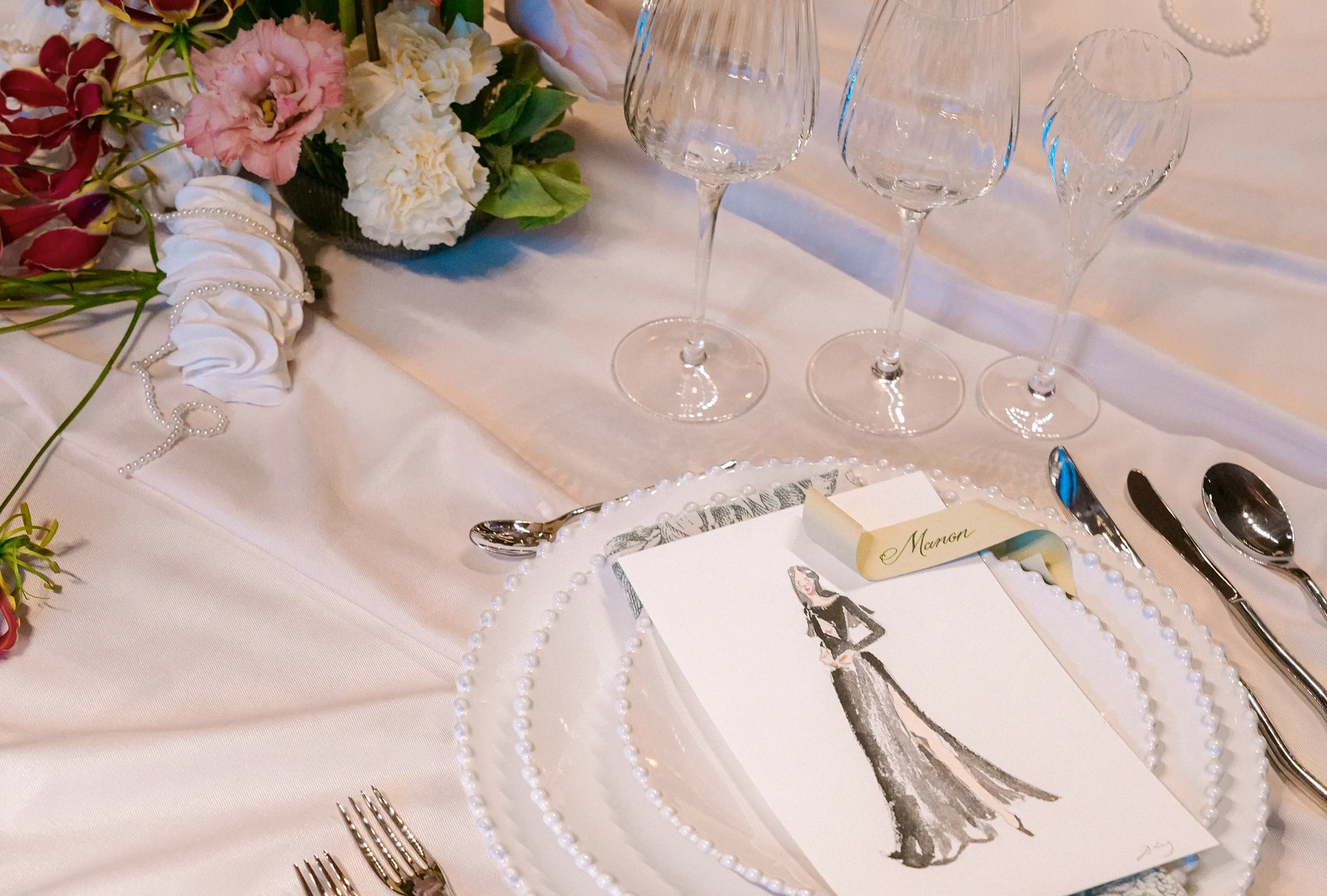 Watercolor guest portrait used as a place card on a wedding table at InterContinental Geneva, beside crystal glasses and flowers. © Laura's Creativity