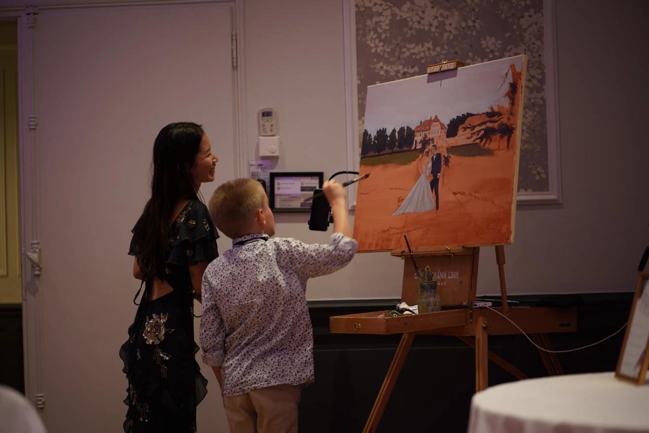 Young wedding guest adding a brushstroke to the live wedding painting at Château de la Tour. Photography by @pichou_.